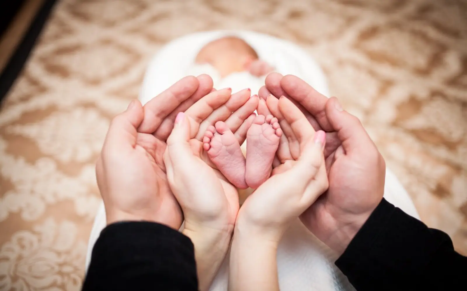 Newborn baby's feet held safely in adult hands